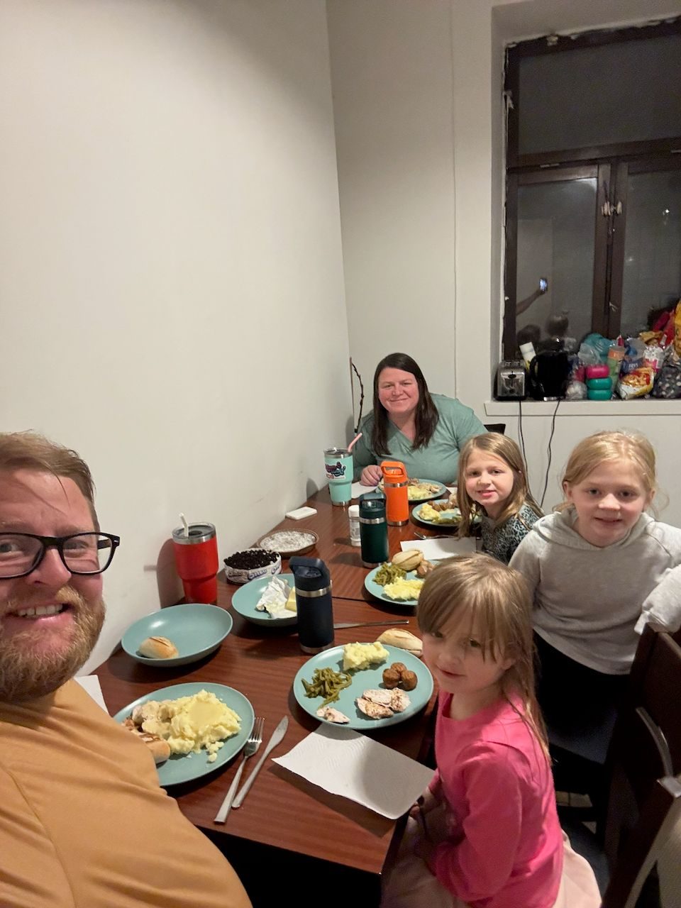 The Clarkson family seated around a Thanksgiving dinner of mashed potatoes and green beans in their Malmö apartment