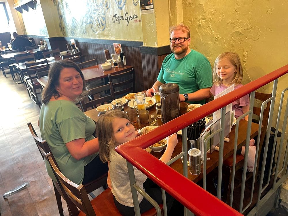 A family sits at a wooden table inside a retro gyoza restaurant in Asakusa, Tokyo, with vintage decor and signage visible on the walls.