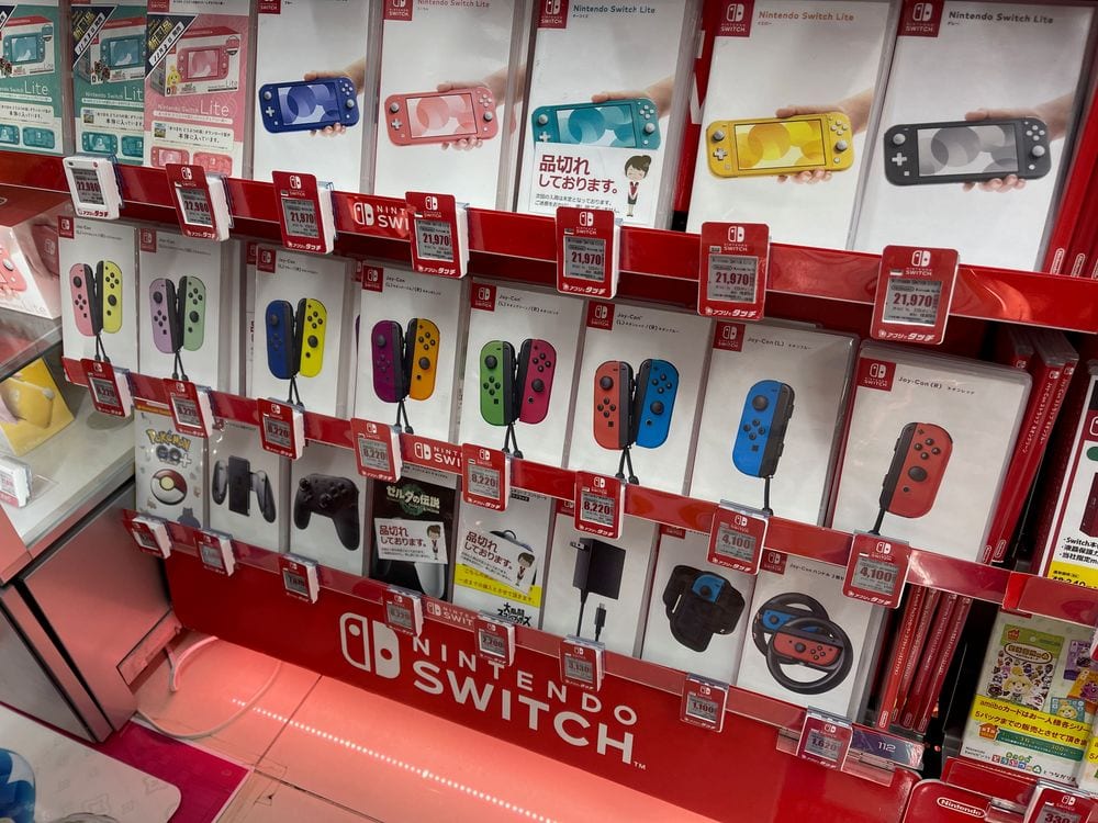 A wall display of Nintendo Switch consoles and accessories inside a Bic Camera electronics store.