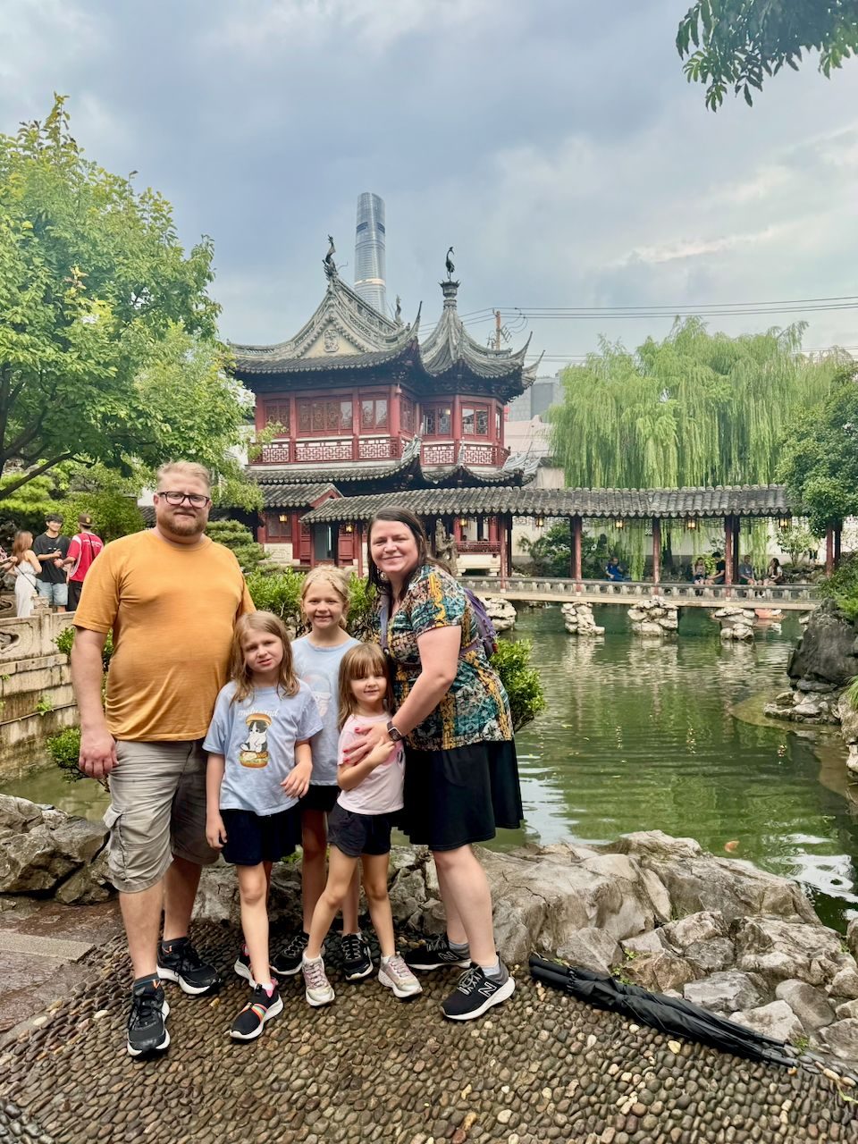 The family poses together in front of the classical pavilions and rockery of Yu Garden in Shanghai