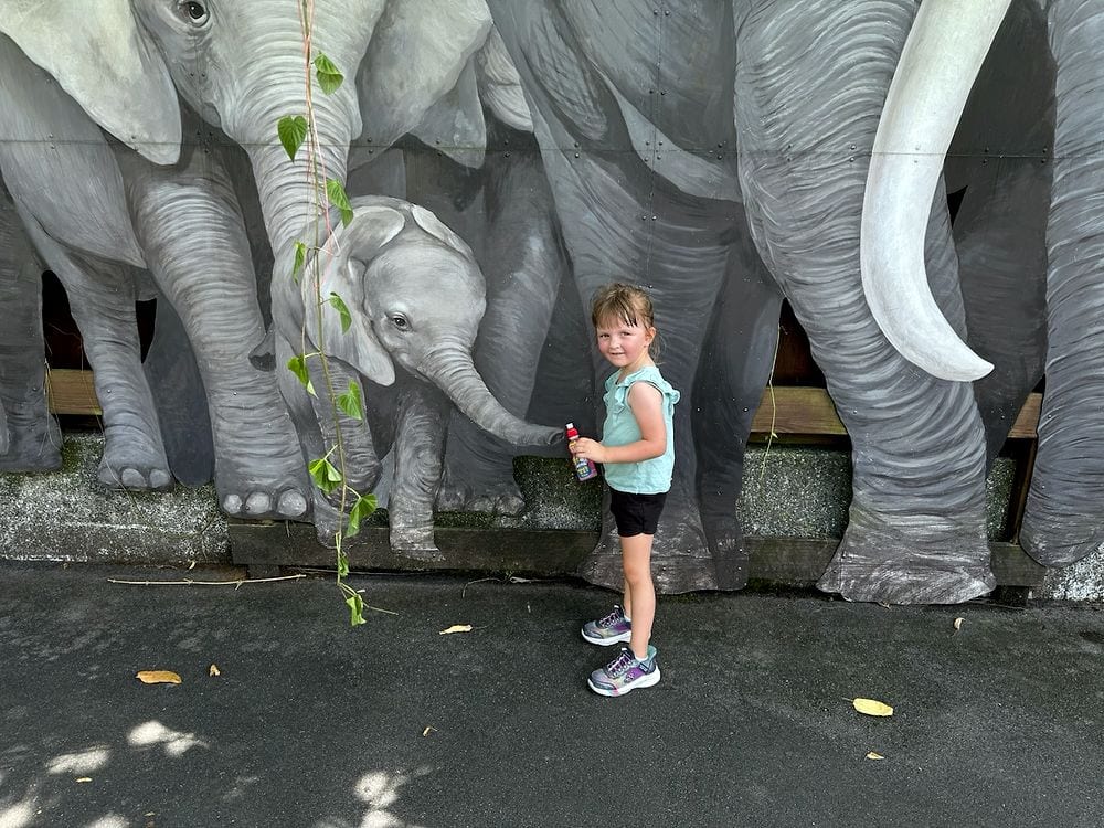 Harper posed with the baby elephant mural at Taipei Zoo, the painted trunk nearly touching her hand.