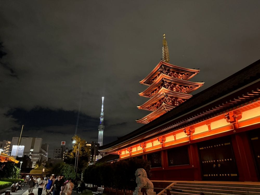 The five-story pagoda at Senso-ji lit up at night with Tokyo Skytree glowing in the background
