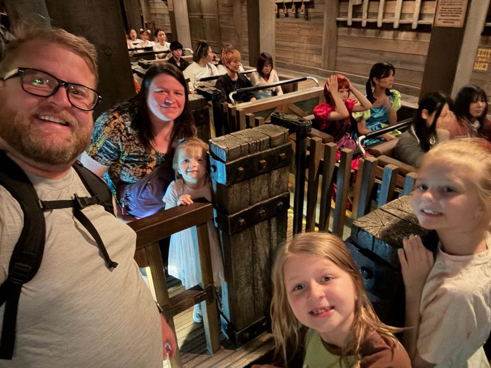 Family of five taking a selfie from a dark ride vehicle at Tokyo Disneyland