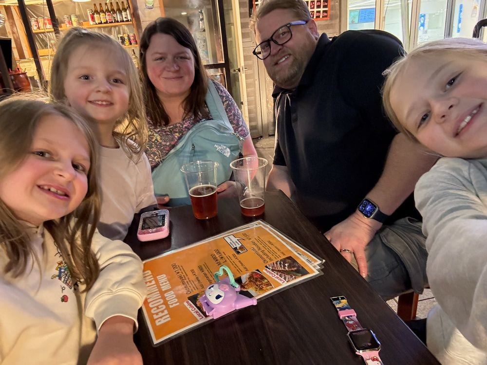 Our family of five taking a selfie at a restaurant table in Dotonbori, Osaka, Japan at night, April 2026
