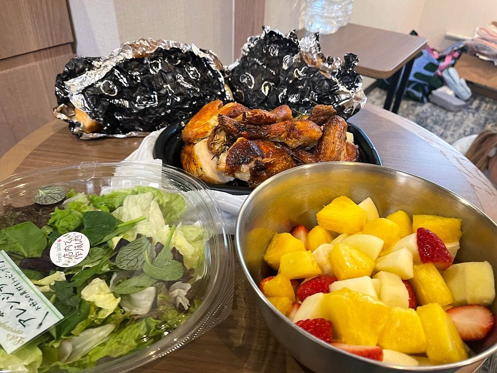 A Thanksgiving-style roast chicken, salad, and fruit salad arranged on a table in a Tokyo apartment.
