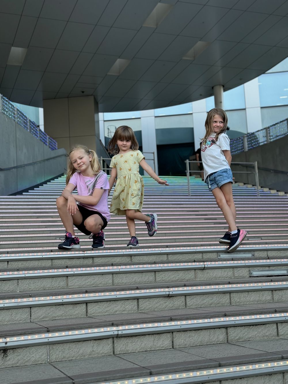Three young girls play on an outdoor staircase near DiverCity Tokyo Plaza in Odaiba.