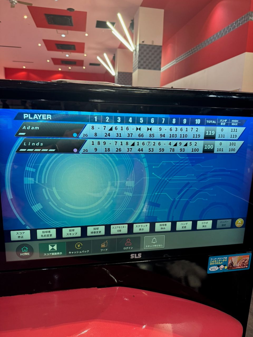 A Japanese bowling alley scorescreen showing two players, Adam with a final score of 119 and Linds with a final score of 100, displayed on a blue digital scoreboard with Japanese text menus along the bottom.