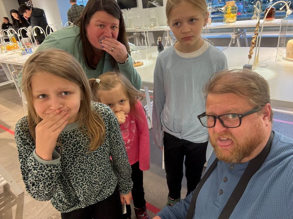 Adam, Lindsay and their three daughters pulling disgusted faces in a selfie at the Disgusting Food Museum in Malmö, Sweden