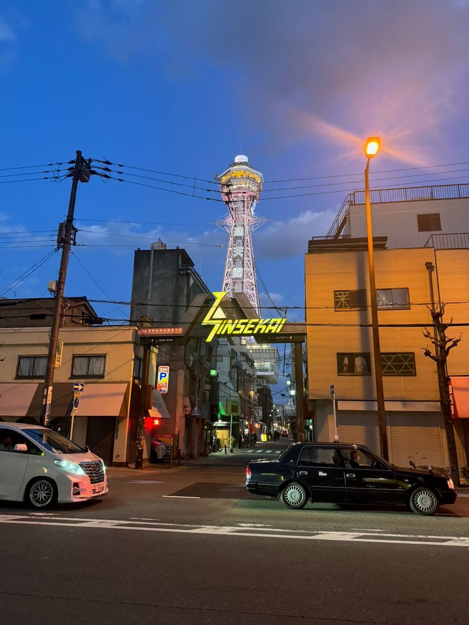 Tsutenkaku tower lit up at blue hour above the Shinsekai gate in Osaka