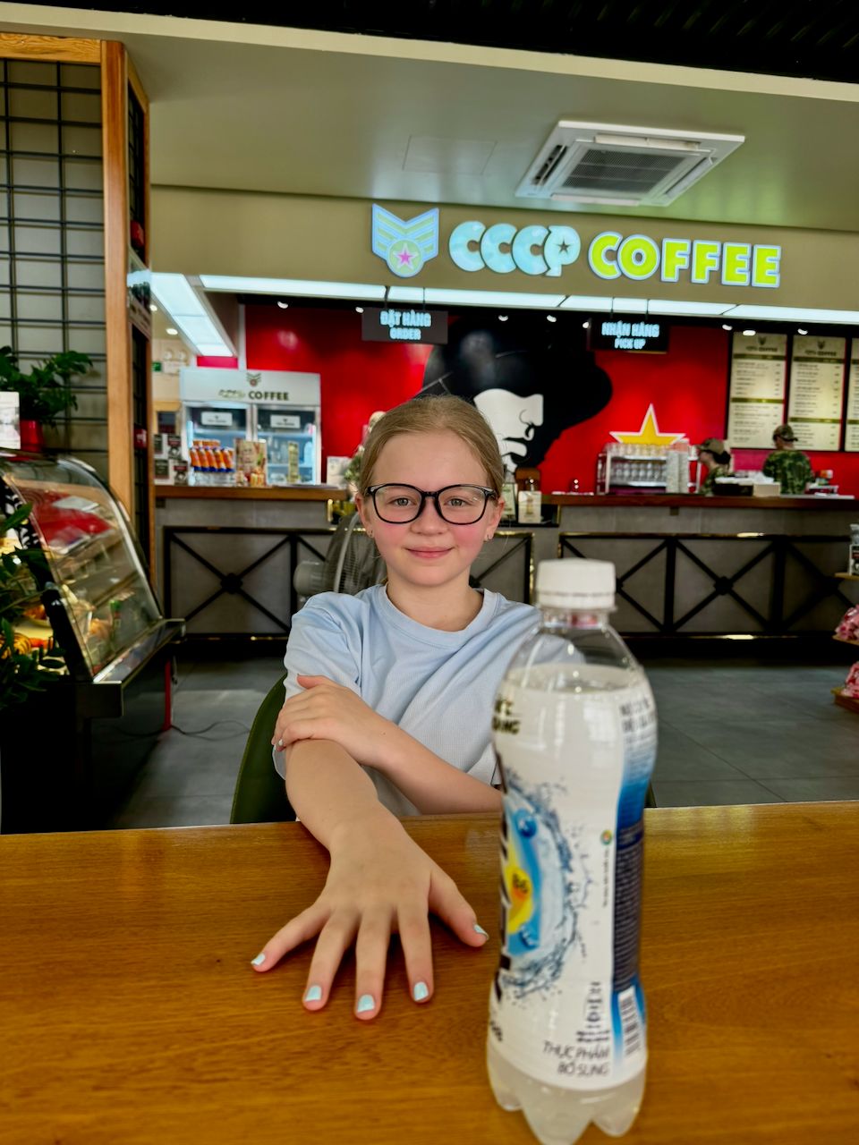 Lily sitting at a wooden table inside CCCP Coffee in Da Nang