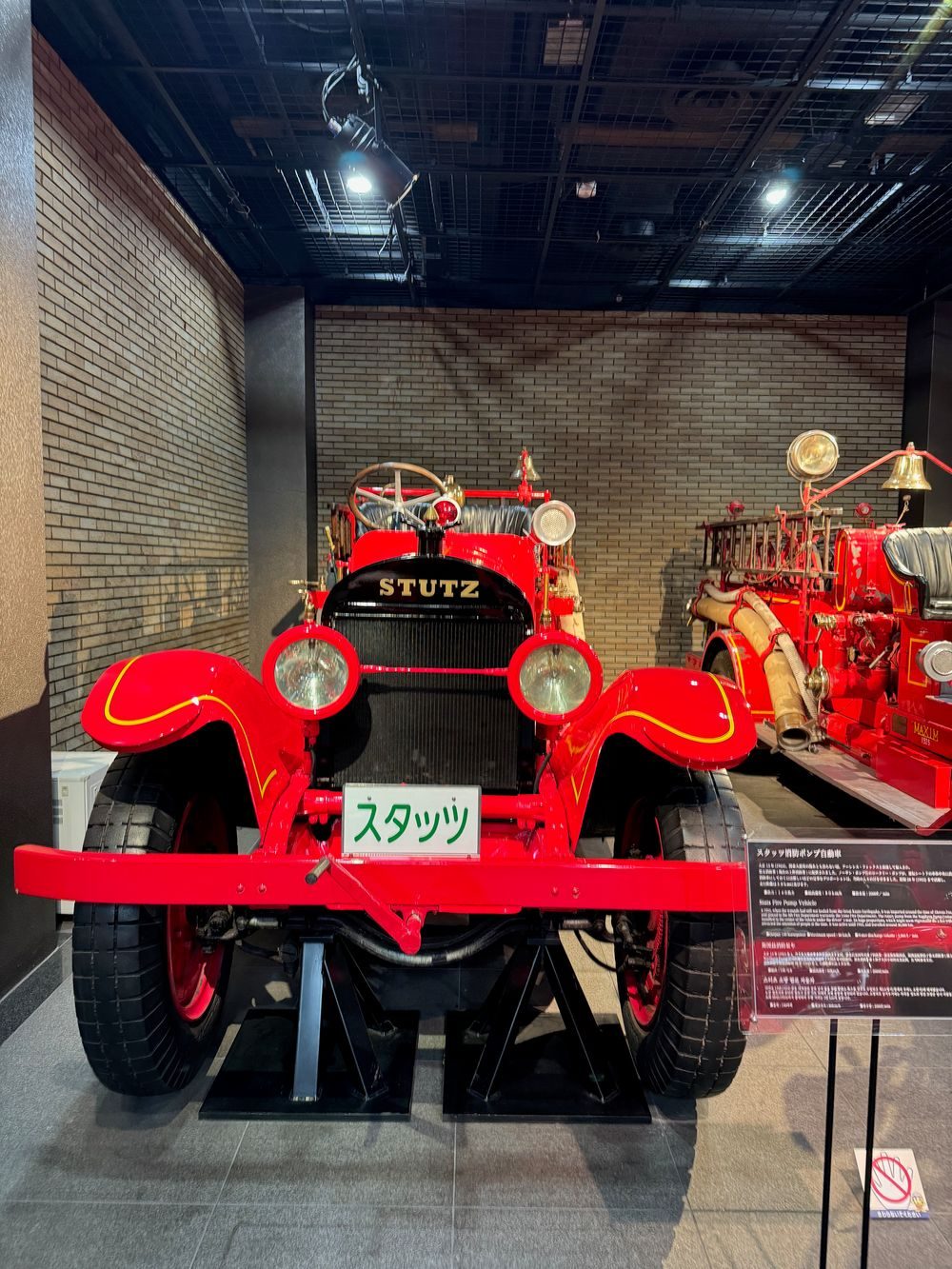 A vintage red STUTZ fire truck on display in the basement of the Tokyo Fire Museum, with another historic fire engine visible behind it.