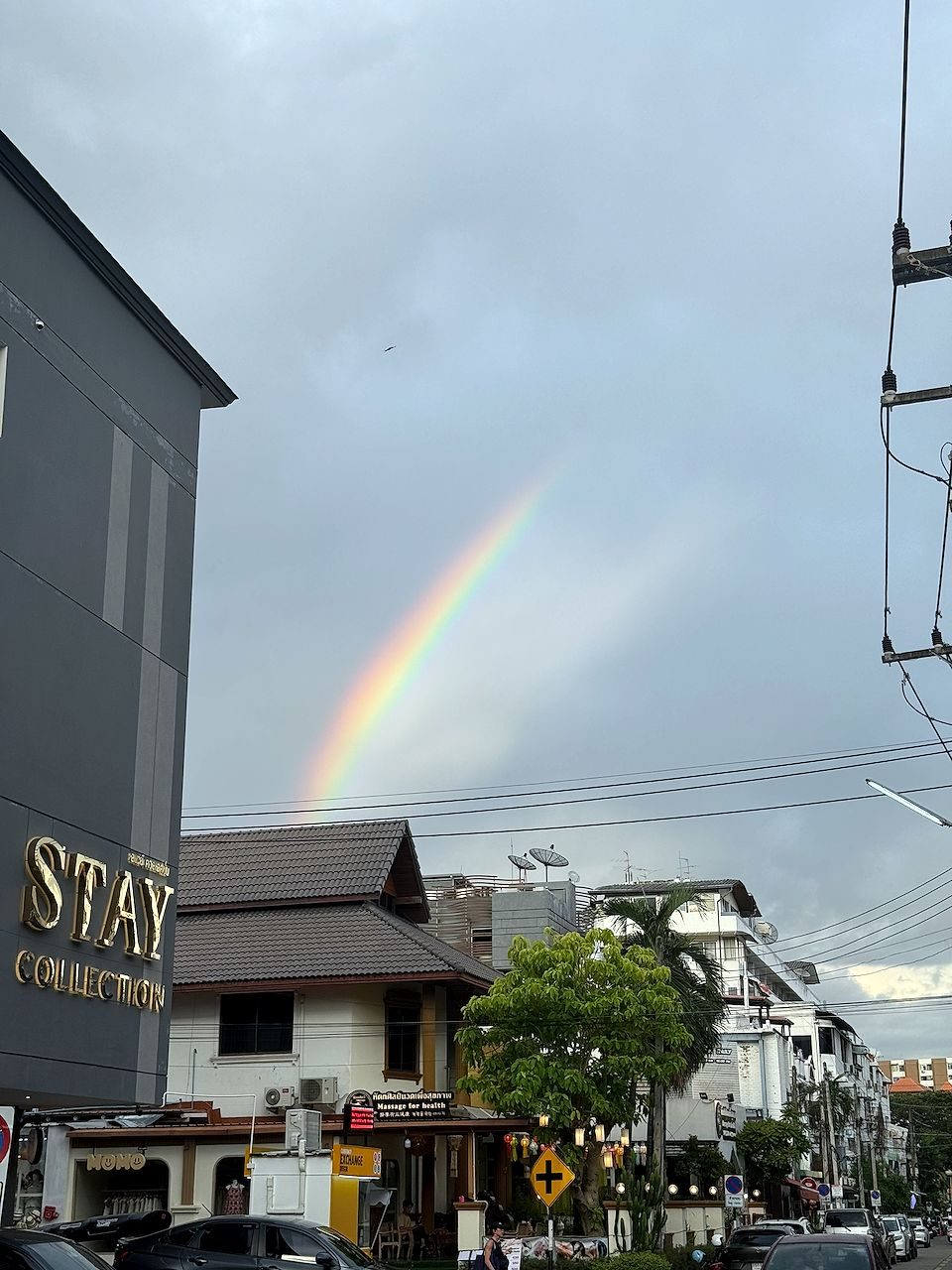 A double rainbow arcs over the rooftops and palm trees of Chiang Mai, Thailand after an evening rain shower