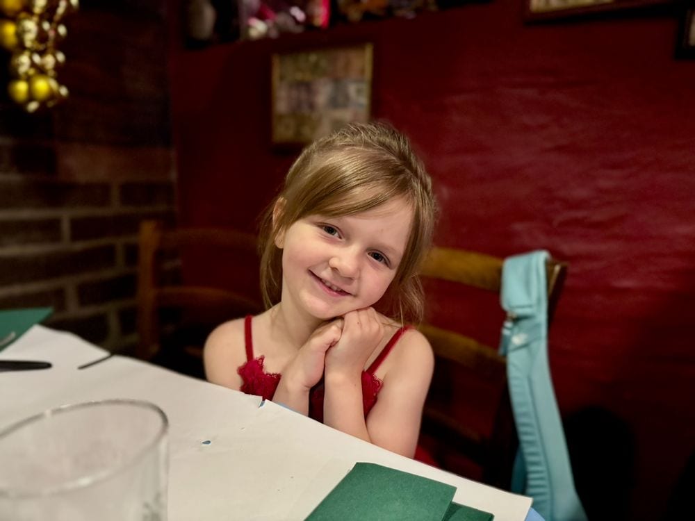 Harper sitting with her chin in her hands at a restaurant table in Nyhavn, Copenhagen, waiting for dinner