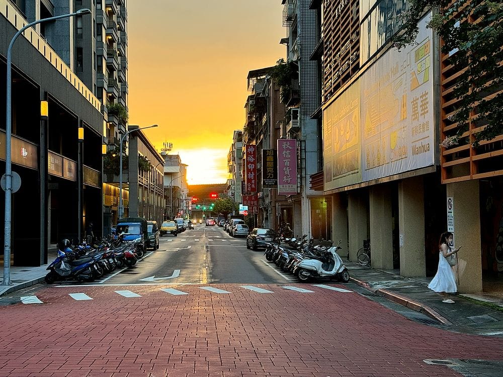 The sunset lined up perfectly with the street in Wanhua, scooters parked on both sides, sky on fire.