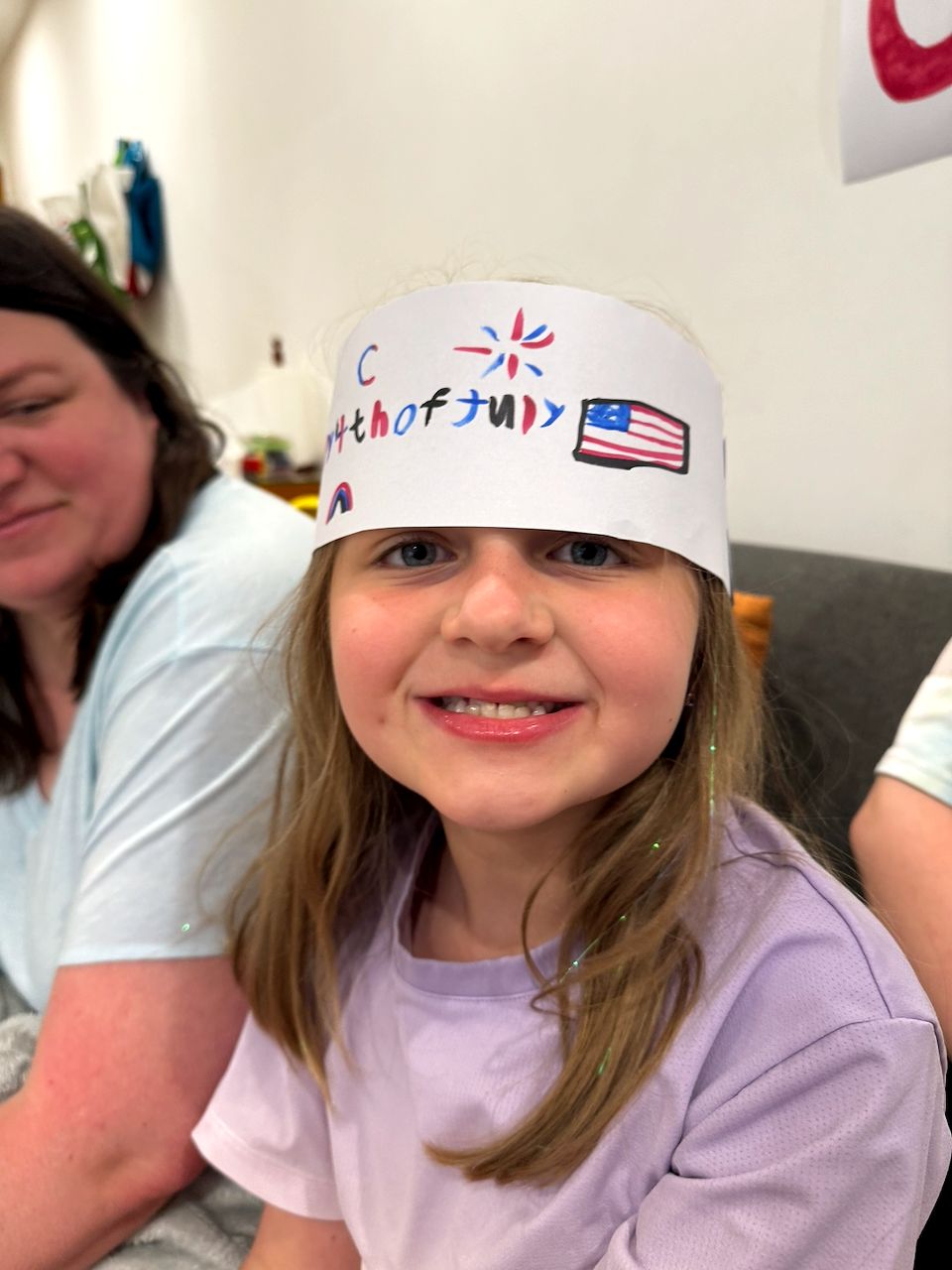 Cora wearing a handmade paper crown reading 4th of July in Da Nang, Vietnam