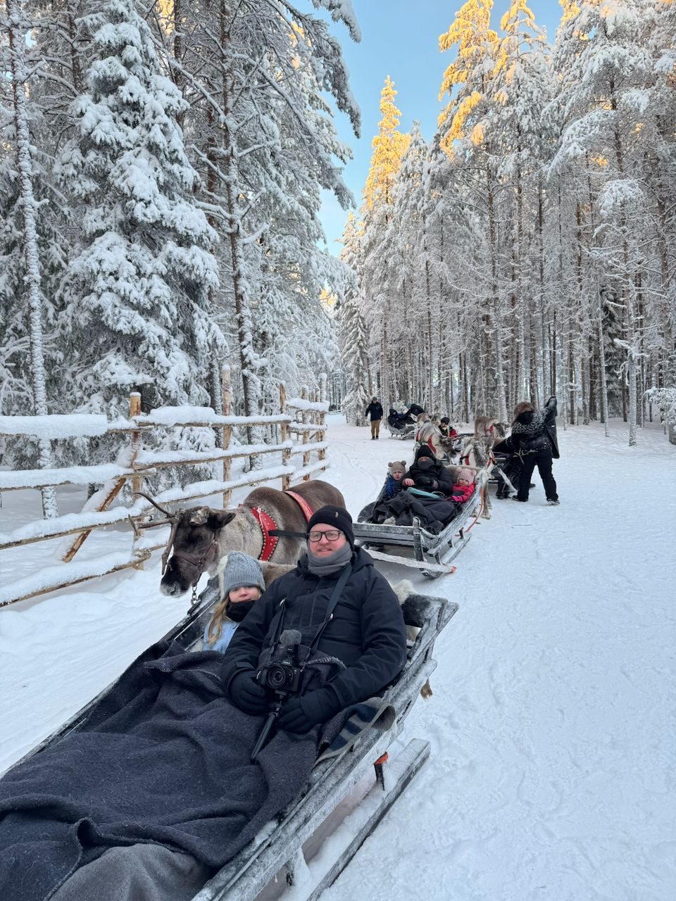 The whole Clarkson family on a reindeer sleigh ride through the snow-covered forest in Lapland