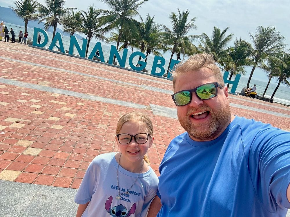 Adam and Lily at the Da Nang Beach sign